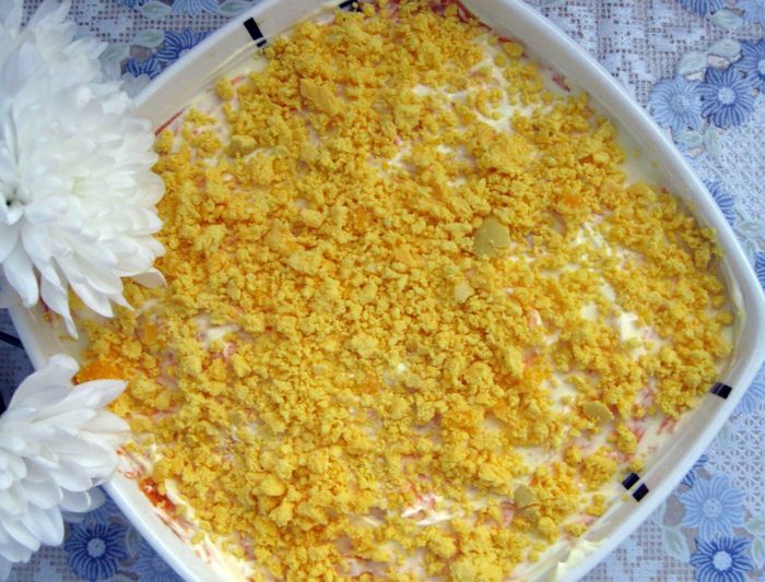 Верхний слой салата заправляем майонезом и украшаем тертым яичным желтком